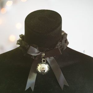 A delicate black satin and gauze choker with large bow design to the front and silver bell decoration. This choker is fixed by tie strings at the back. 